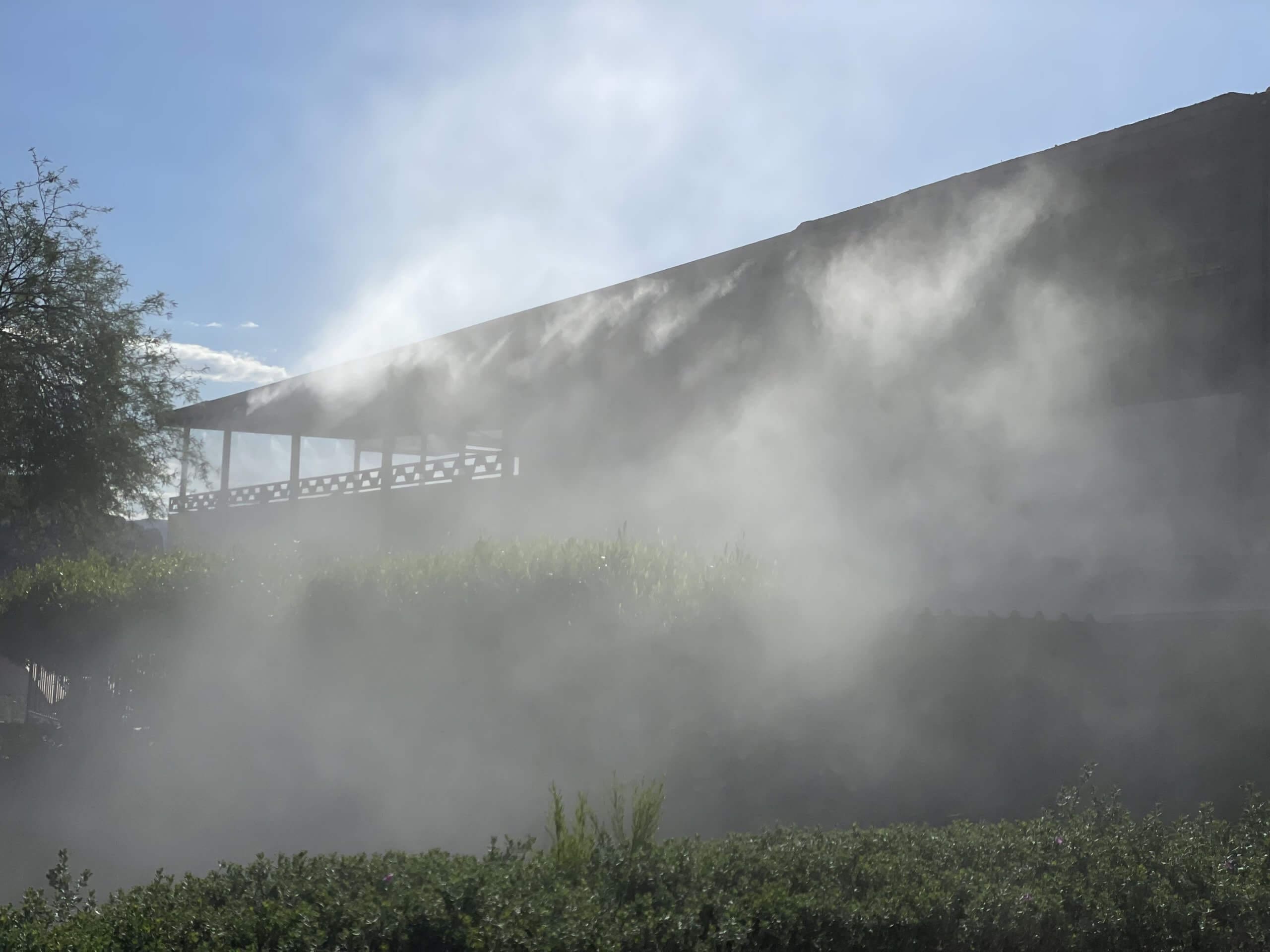 Residential fogging system creating a mist effect around a building, enhancing landscape aesthetics and promoting serene outdoor environments.